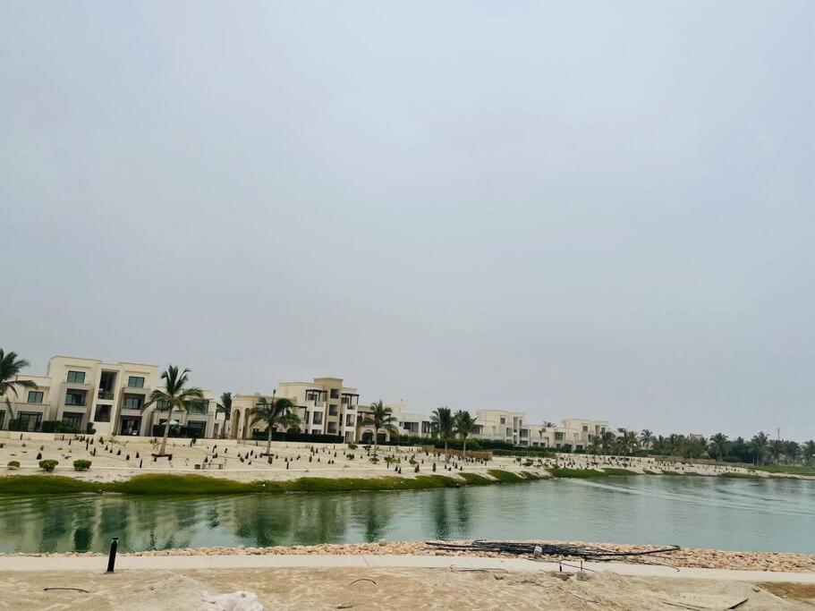 a beach with people and buildings and a body of water at one bedroom villa in Salalah