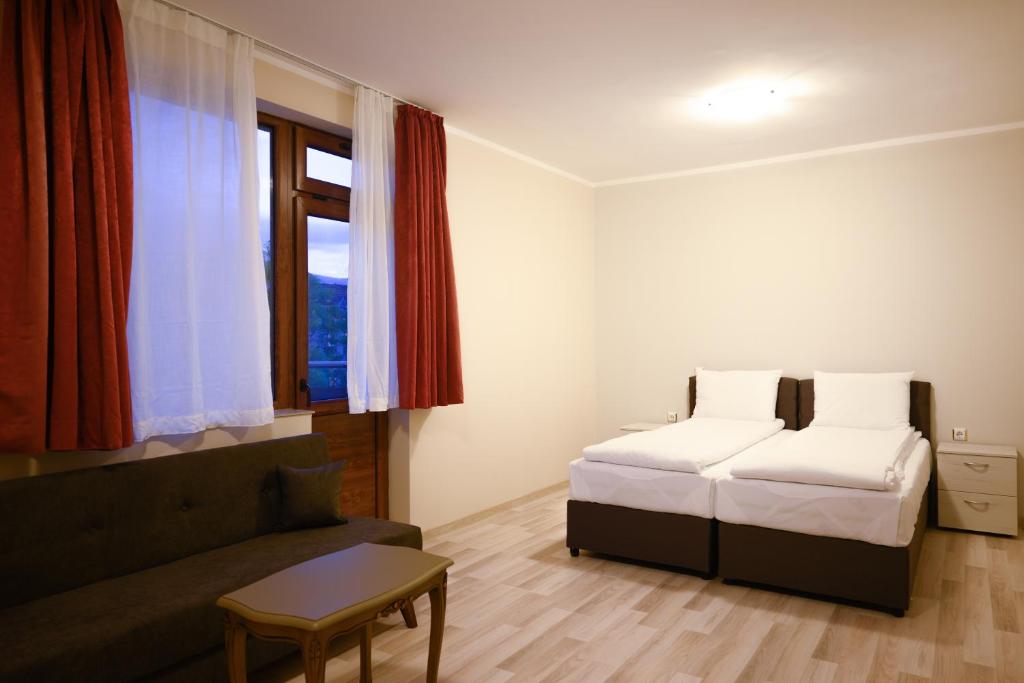 a bedroom with two beds and a couch and a window at Hotel Leda in Sofia