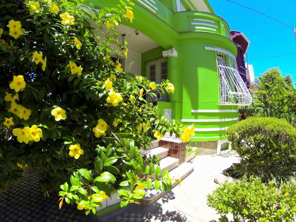 uma casa verde com flores amarelas em frente em POA Eco Hostel em Porto Alegre