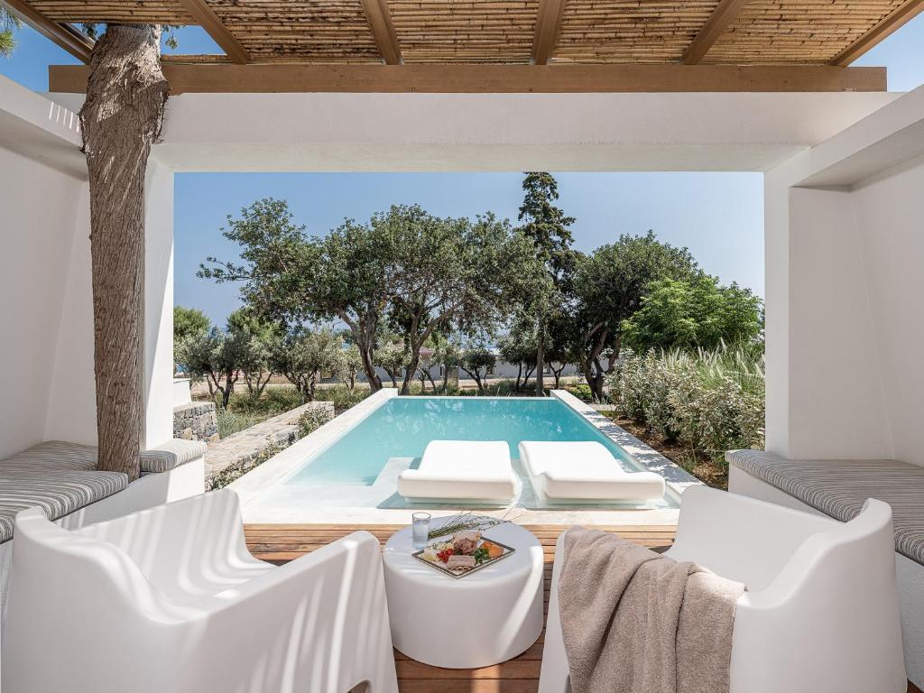 uma piscina com cadeiras brancas e uma mesa em Kakkos Bay Hotel and Bungalows em Lerápetra