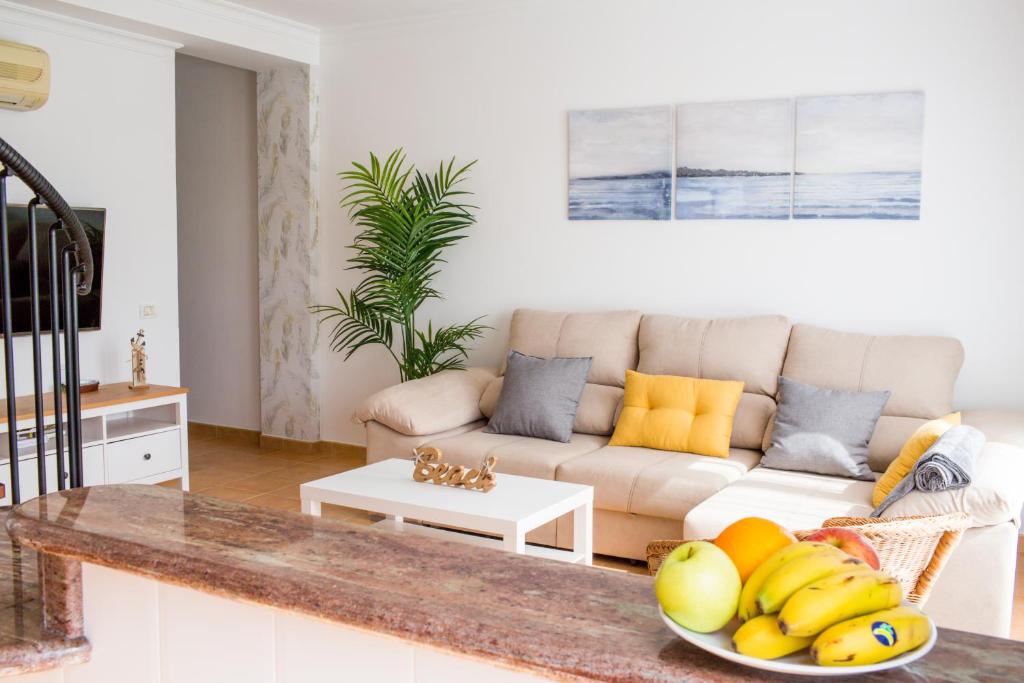 un soggiorno con divano e cesto di frutta di Home2Book Ático Blue Beach, Pool&Terrace a Sardina