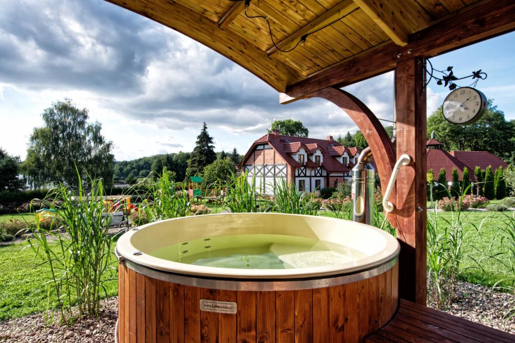a hot tub in a garden with a clock at Uroczysko Lutówko in Sępólno Krajeńskie