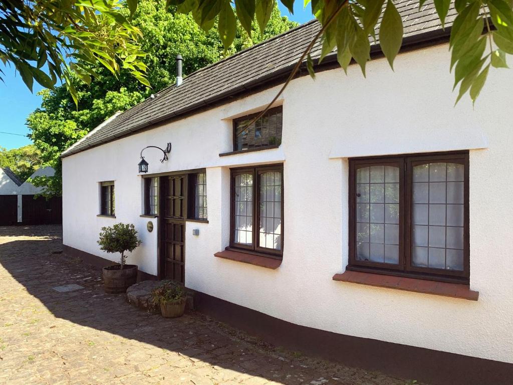 a white house with windows and a door at Stables Cottage in Dunster