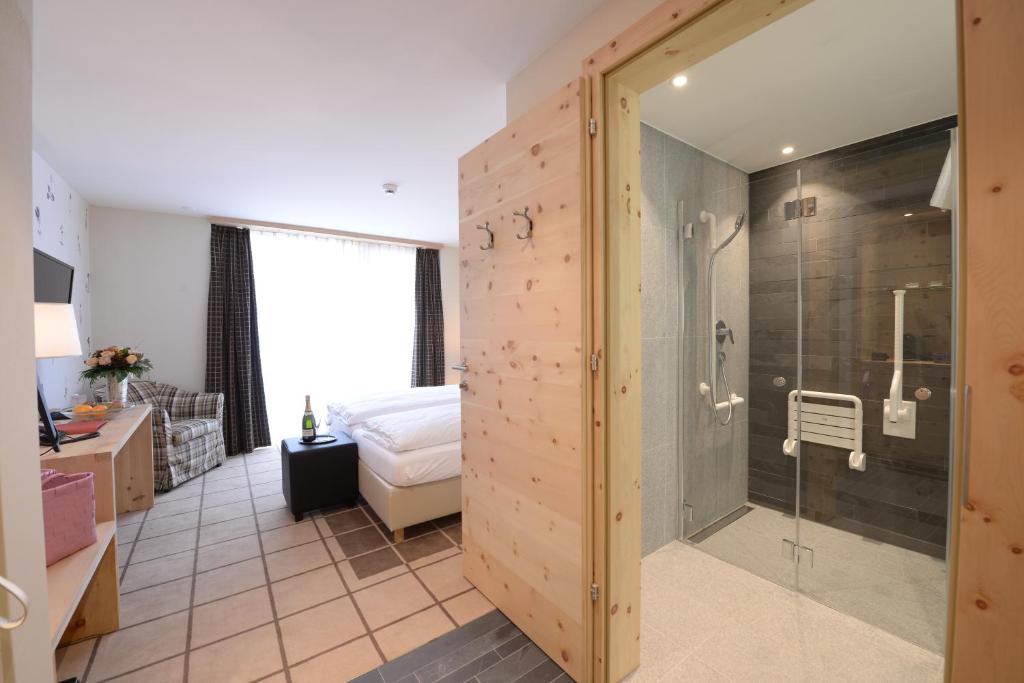 a bathroom with a shower and a bed in a room at Alpenhotel Fleurs de Zermatt in Zermatt