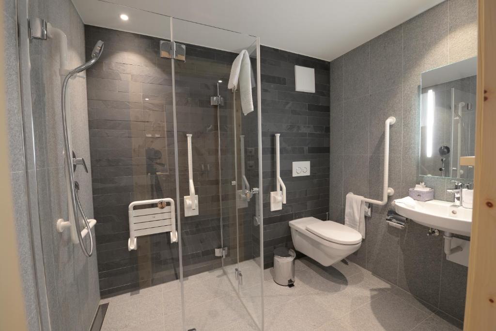 a bathroom with a shower and a toilet and a sink at Alpenhotel Fleurs de Zermatt in Zermatt