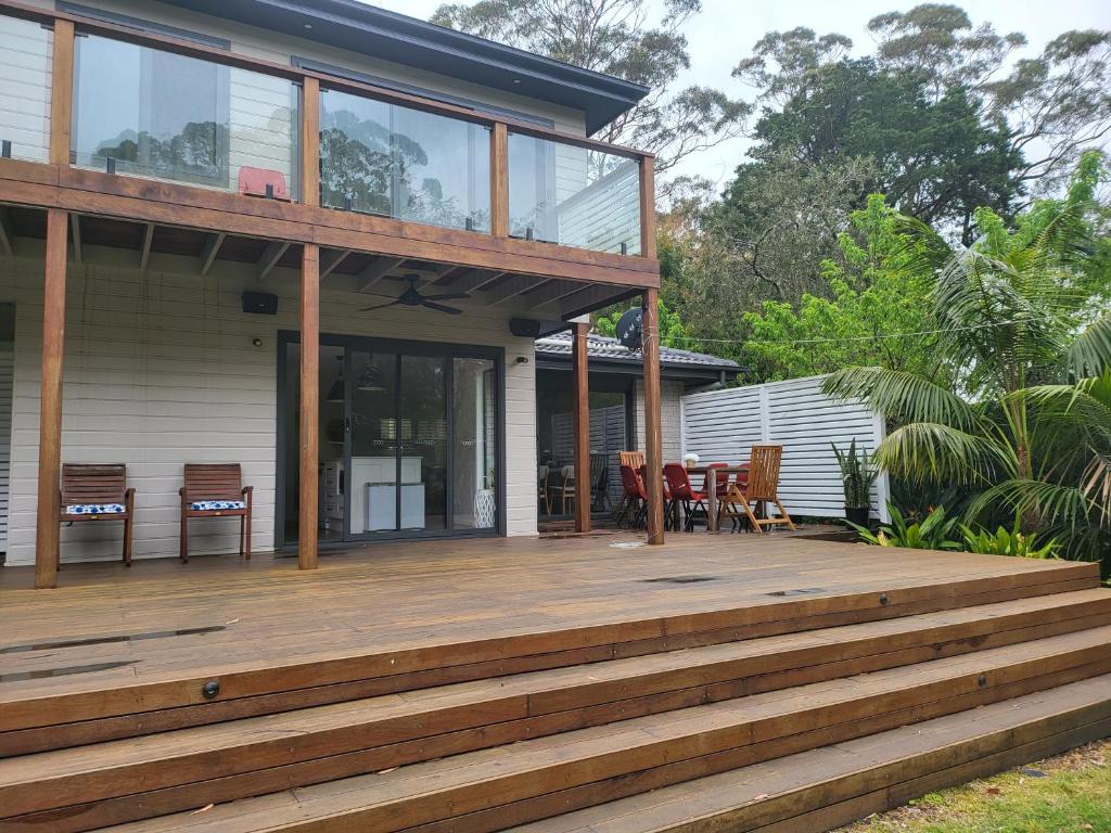 a house with a large wooden deck at Jervis Bay Waters Edge Retreat - Access to Deep Water - Free late check out 2pm on Sundays, low season in Woollamia