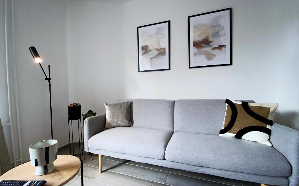 a living room with a couch and two pictures on the wall at MILPAU Gladbeck 1 - Modernes und zentrales Premium-Apartment mit Privatparkplatz, Queensize-Bett, Netflix, Nespresso und Smart-TV in Gladbeck