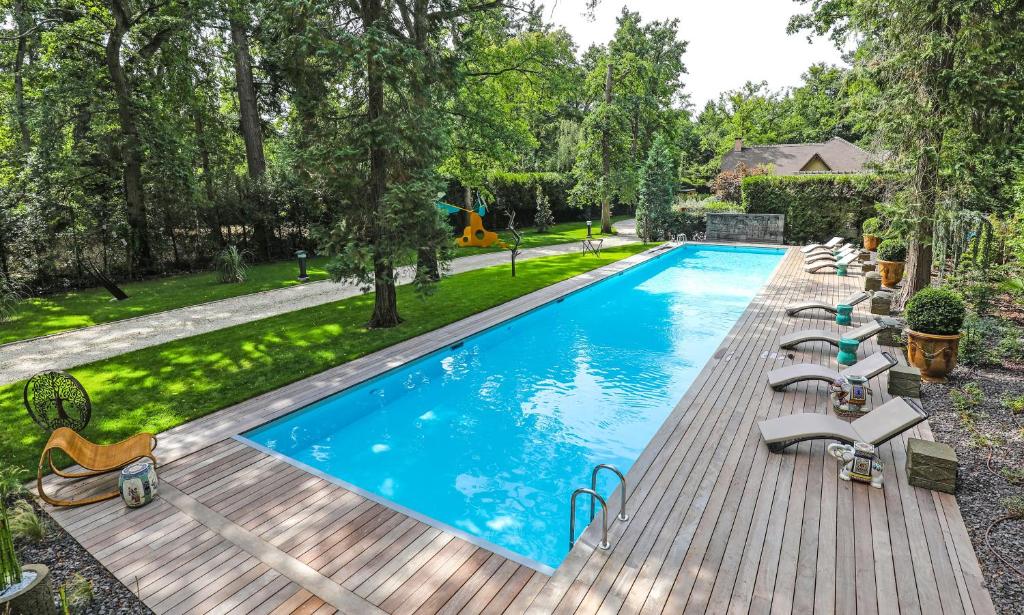 uma imagem de uma piscina com espreguiçadeiras num deque de madeira em The Iflissen Pavilion - Luxury Villa em Lamorlaye