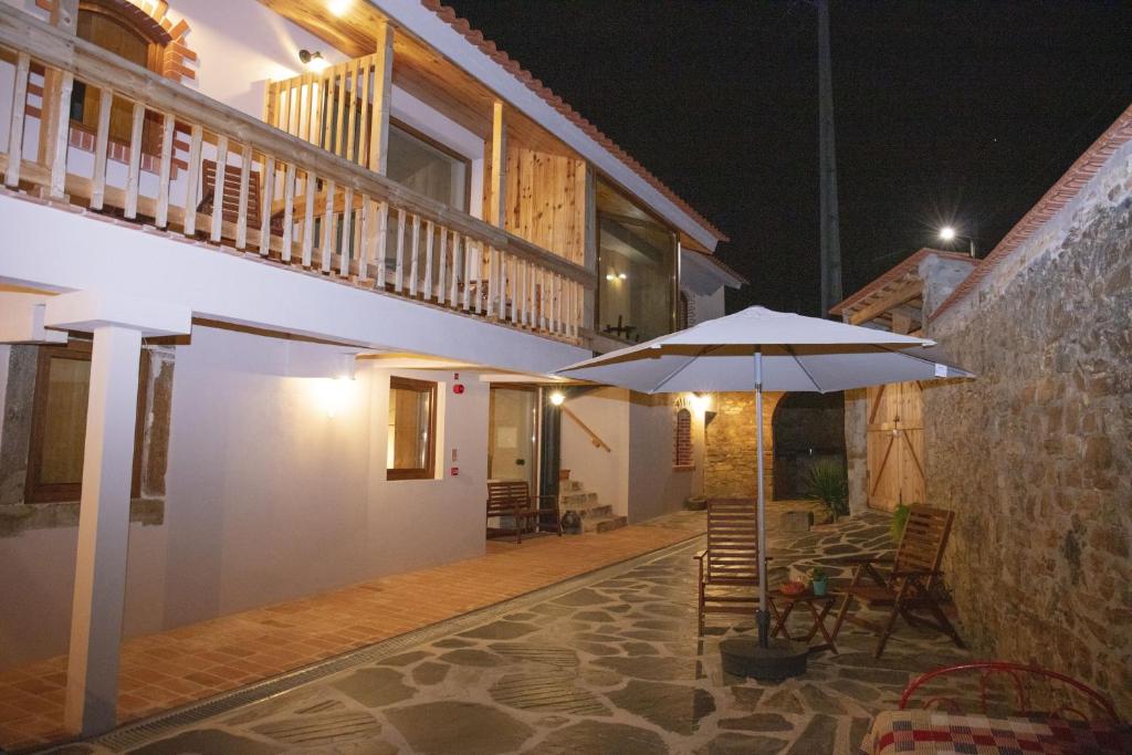 a patio with a table and an umbrella at night at Vale das Maias - Casa de Campo in Laborins