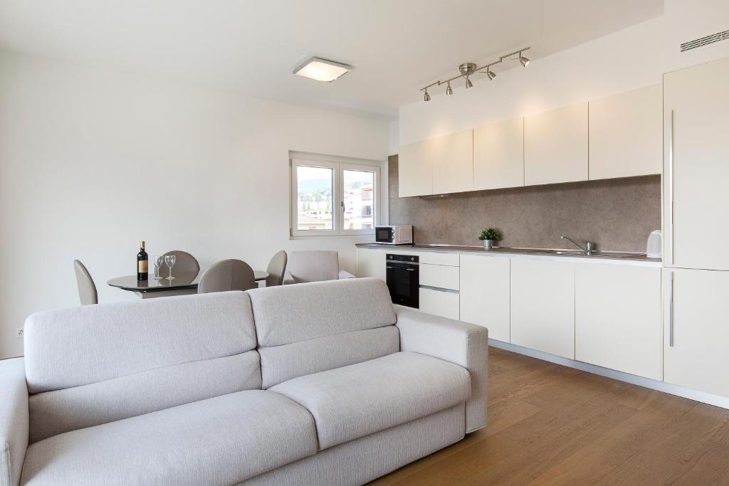un soggiorno bianco con divano e cucina di Roggia 16 by Quokka 360 - central flat with balcony a Viganello