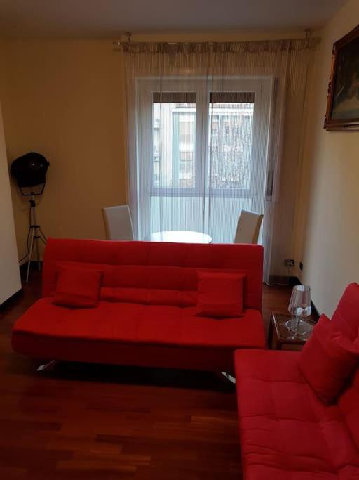 sala de estar con sofá rojo y ventana en Appartamento bello a Milano, en Milán