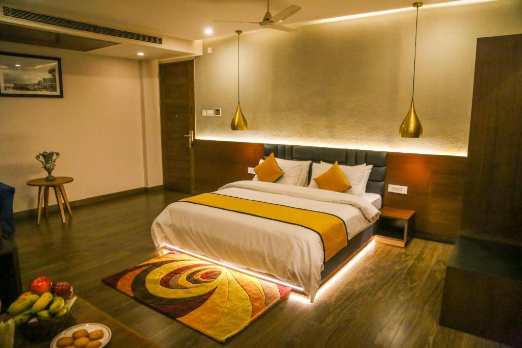 Four Leaf Hotel - Sapphire Blue, Varanasi في فاراناسي: غرفة نوم مع سرير كبير ووعاء من الفواكه