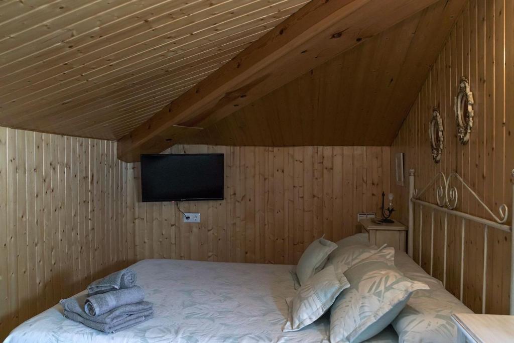 a bedroom with a bed with a tv on the wall at Casa Rural Las Cuevas de Setenil in Setenil