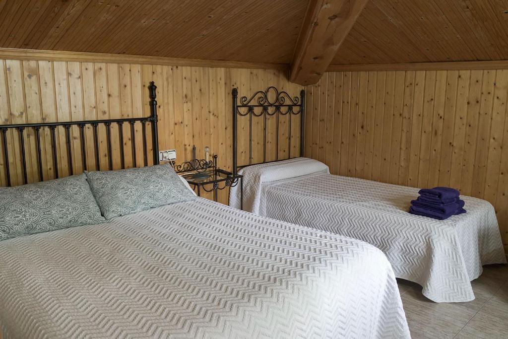 two beds in a room with wooden walls at Casa Rural Las Cuevas de Setenil in Setenil