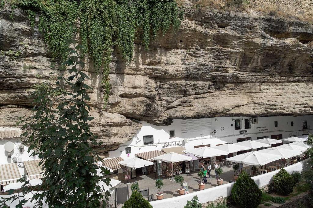 a building next to a cliff with a mountain at Casa Rural Las Cuevas de Setenil in Setenil