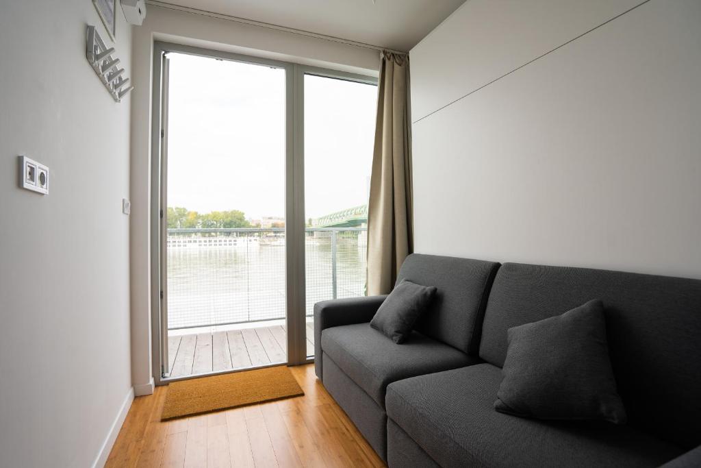 a living room with a couch and a large window at Sundeck botel - party boat in Bratislava