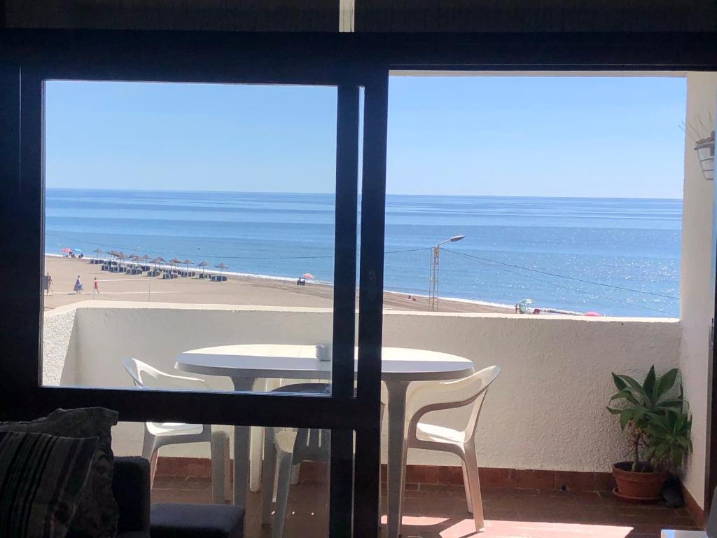 a view of the beach from a room with a table and chairs at Bellamar in Torre de Benagalbón