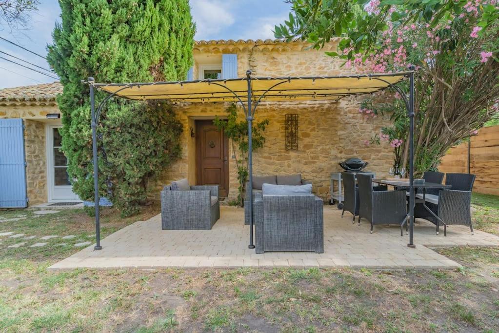 una pérgola con sillas y mesas frente a una casa en Mazet Magnan, Rustic Luxury in Provence, en Piolenc