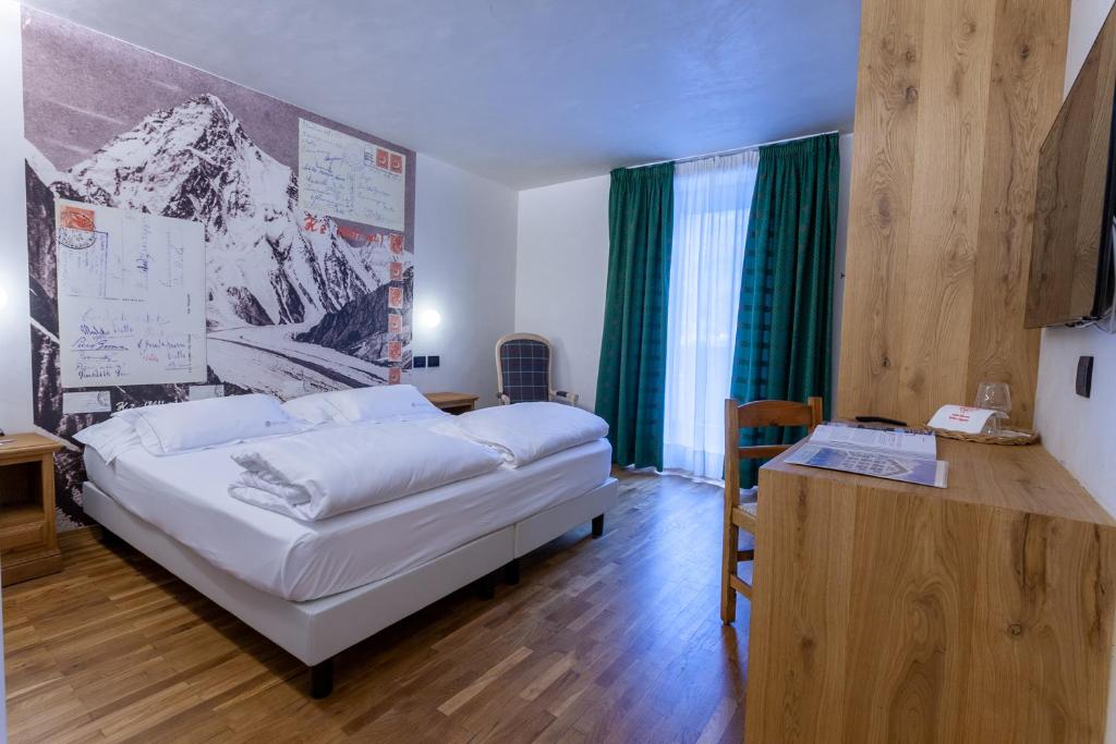 a bedroom with a white bed and a desk with a desk at Hotel Berthod in Courmayeur