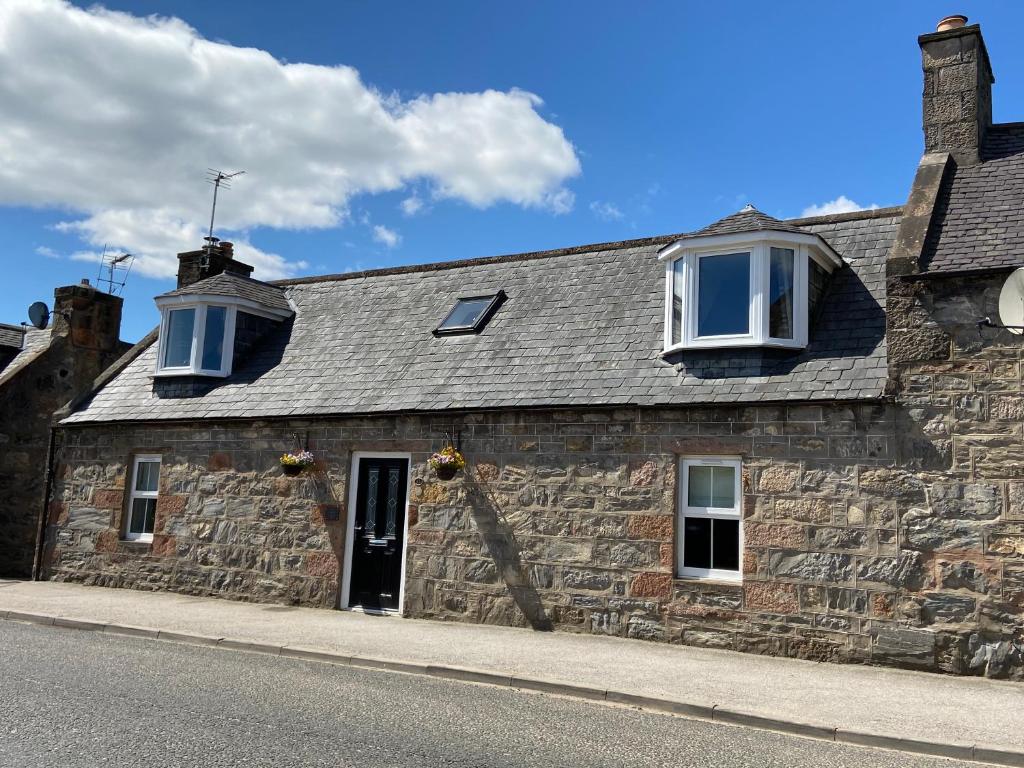 an old stone building with two windows and a door at Islas Cottage, a home in the Heart of Speyside in Dufftown