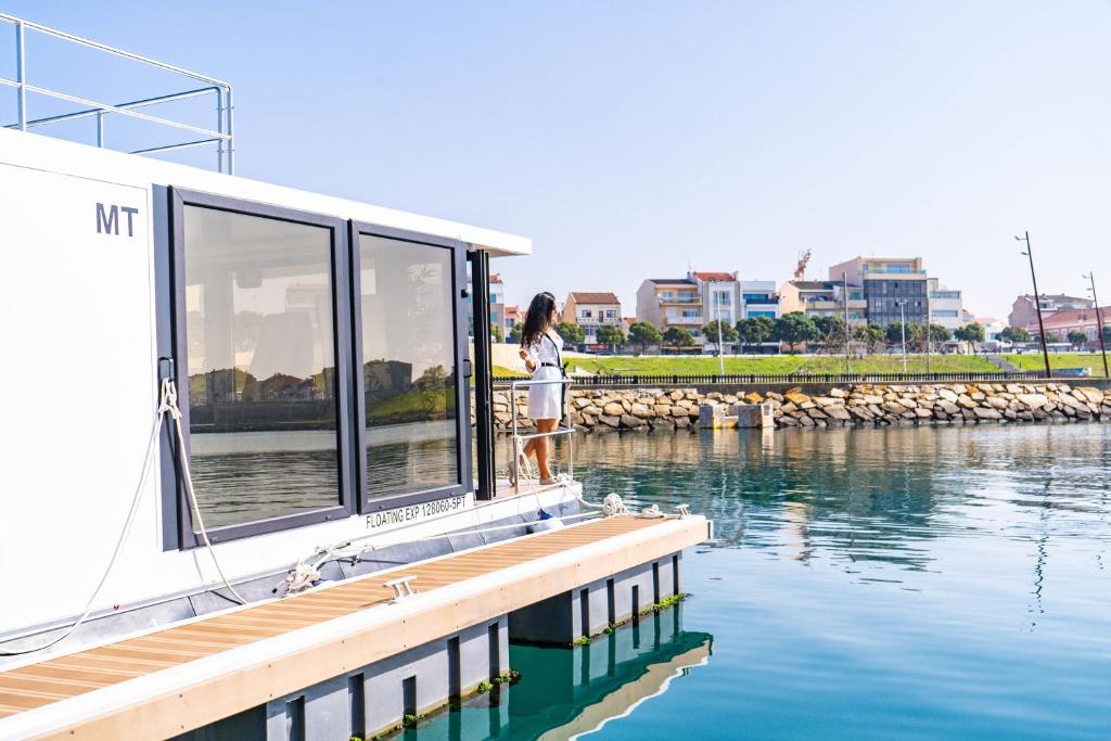 una mujer parada en el costado de un barco en el agua en Floating Experience - Casa flutuante a 25 min do Porto, en Póvoa de Varzim