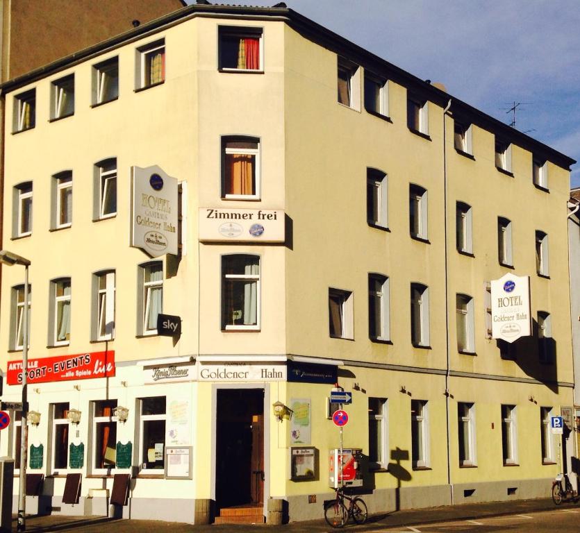 a large white building on the corner of a street at Hotel Goldener Hahn in Duisburg