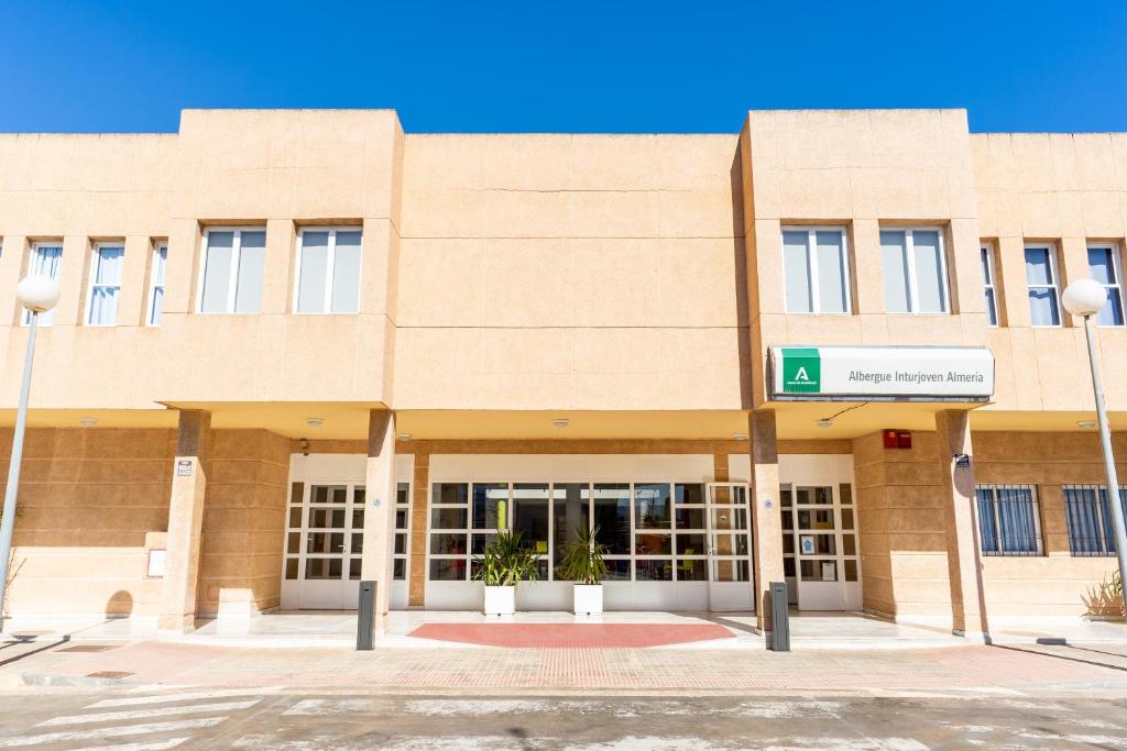 a large brick building with a street sign in front at Albergue Inturjoven Almeria in Almería