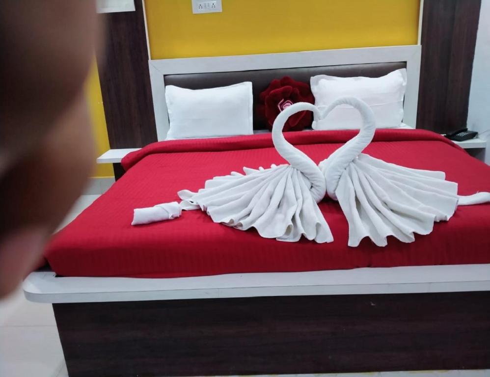 een bed met twee witte zwanen die een hart maken bij Hotel Firdous Palace, Surajpur Chhattisgarh 