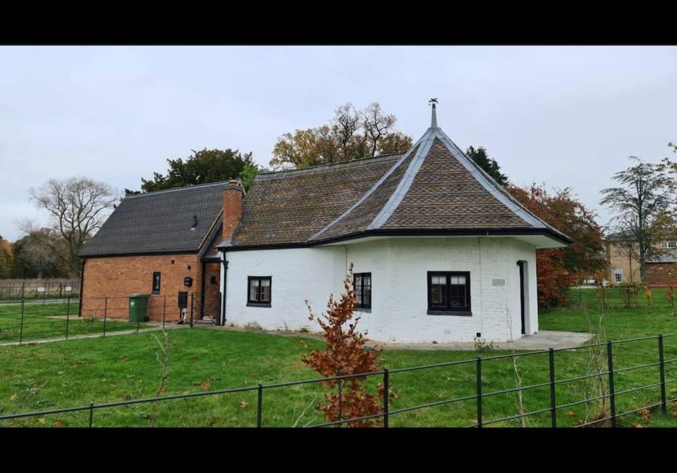 una casa blanca con un techo negro en un campo en The Dairy - Contemporary 1 bedroom cottage, 