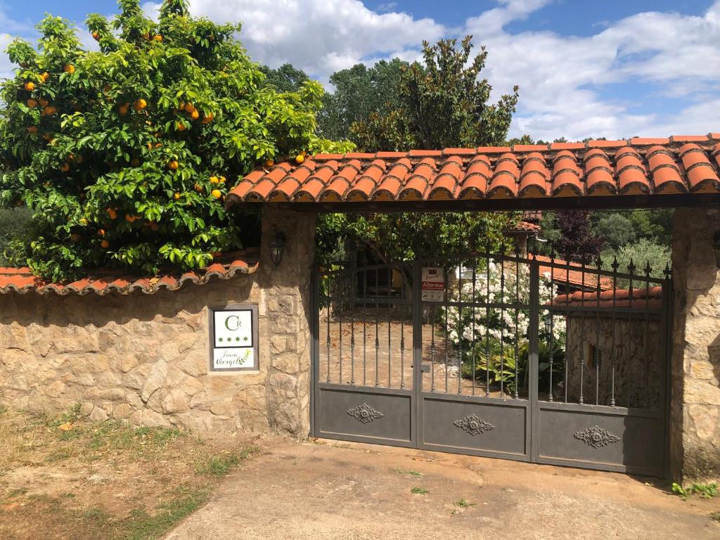 a gate to a house with an orange tree at Finca Vergel in Gata