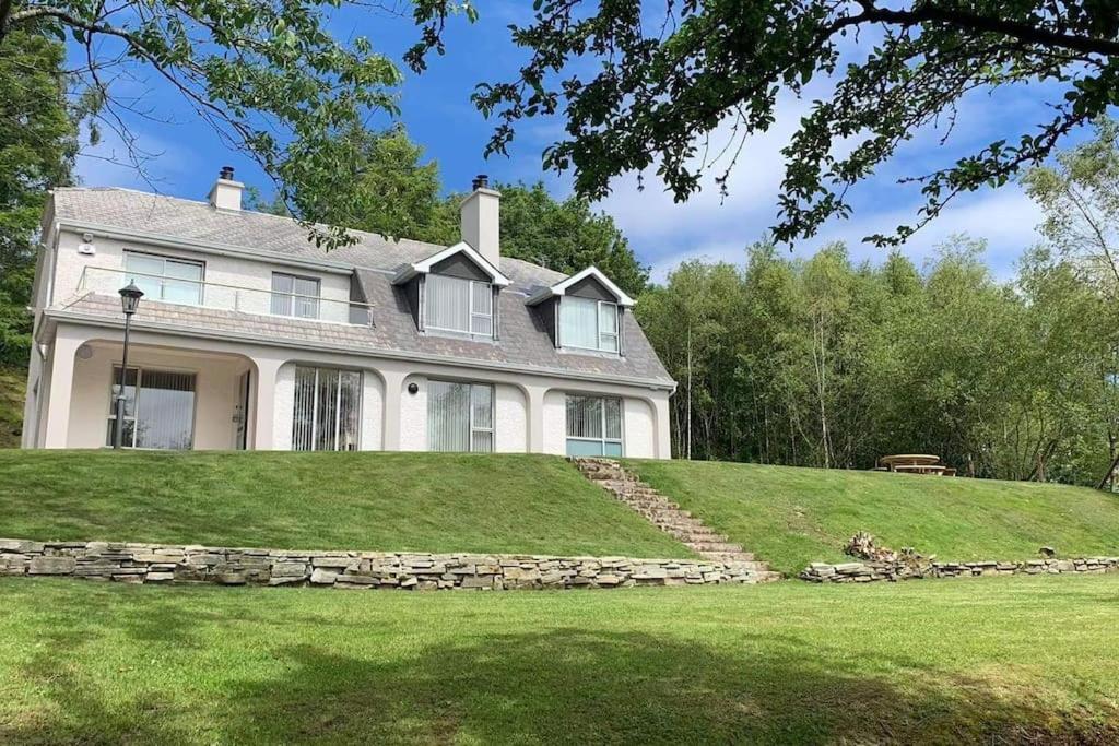 una grande casa bianca in cima a una collina erbosa di Rarooey House a Donegal