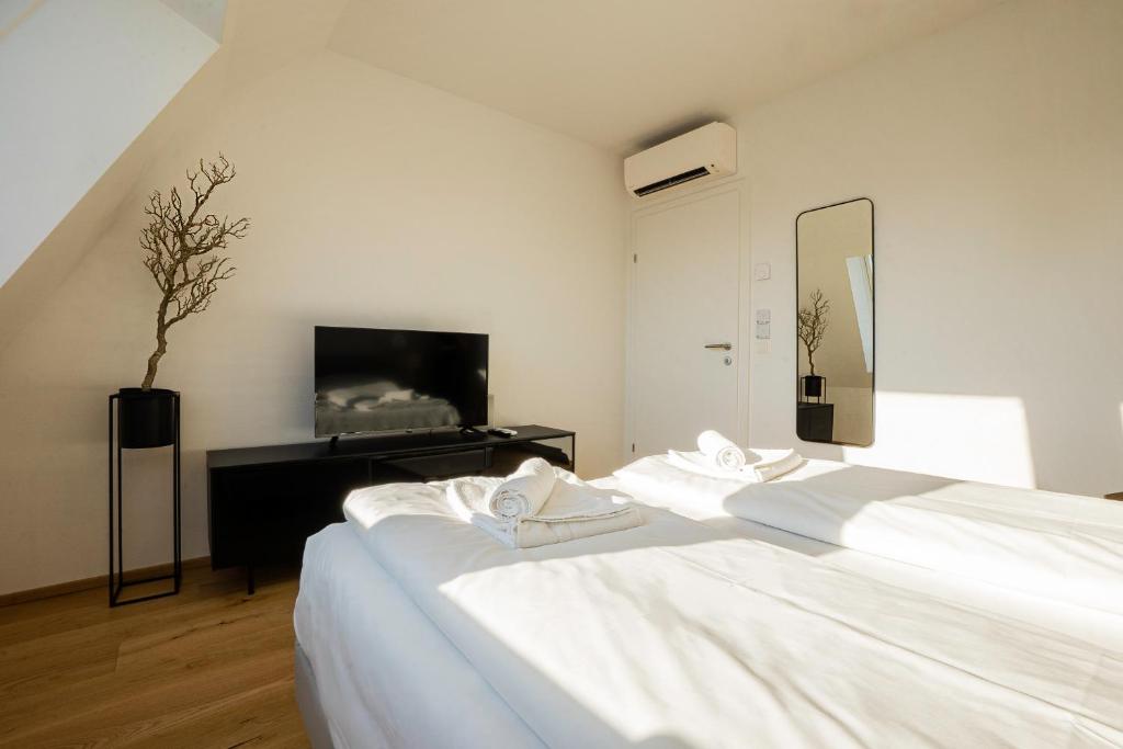 sypialnia z 2 białymi łóżkami i lustrem w obiekcie OrestaLiving - Penthouse with designer renovation w Wiedniu