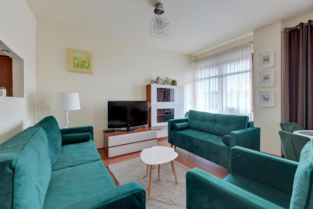 a living room with two green couches and a tv at Dom & House - Apartamenty Neptun Park in Gdańsk
