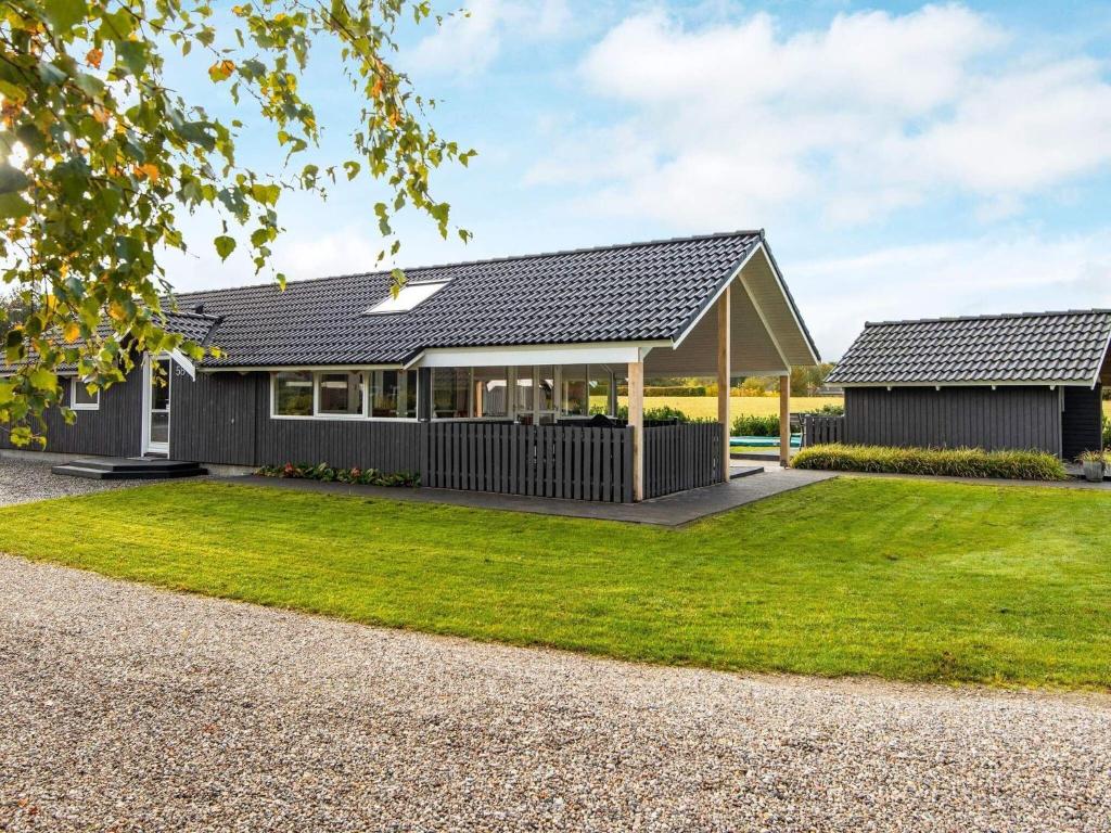 a house with a black roof and a green yard at 8 person holiday home in Hovborg in Hovborg