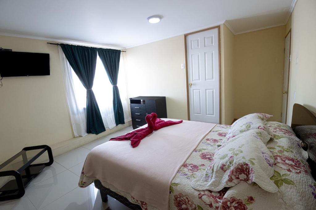 Un dormitorio con una cama con una cinta rosa. en Hostal Beatriz Taltal, en Taltal