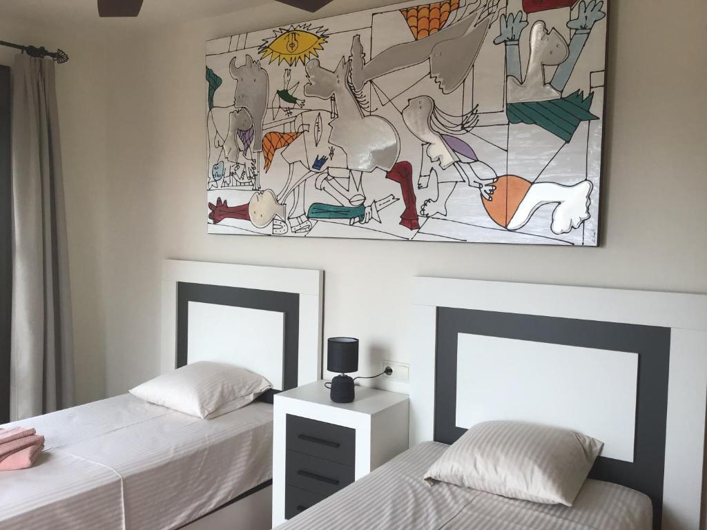 a bedroom with two beds and a painting on the wall at Rincón de Vera - Ático in Vera