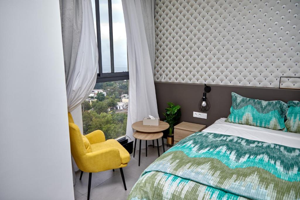 a bedroom with a bed and a yellow chair and a window at Waypoint Suites in Dakar