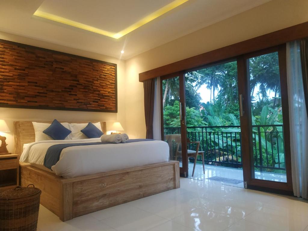 a bedroom with a large bed and a balcony at Cahaya Guest House in Ubud