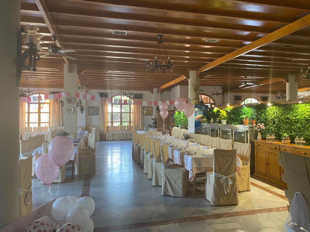 a large banquet hall with white tables and chairs at Hotel Meson Fuente del Pino in Olvera