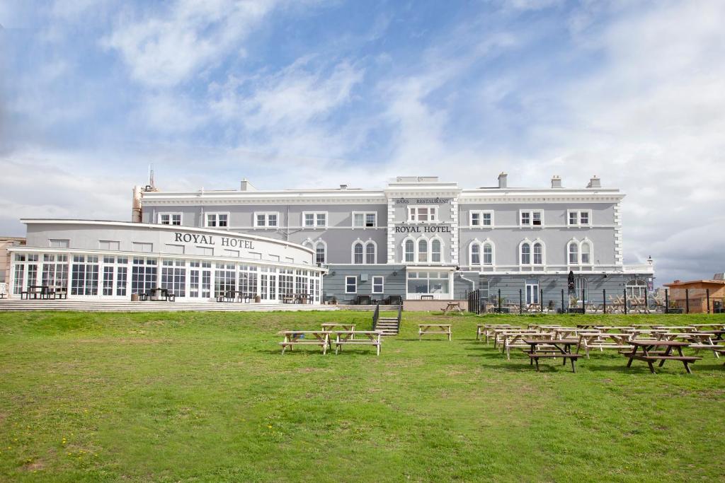 een groot wit gebouw met picknicktafels ervoor bij The Royal Hotel in Weston-super-Mare