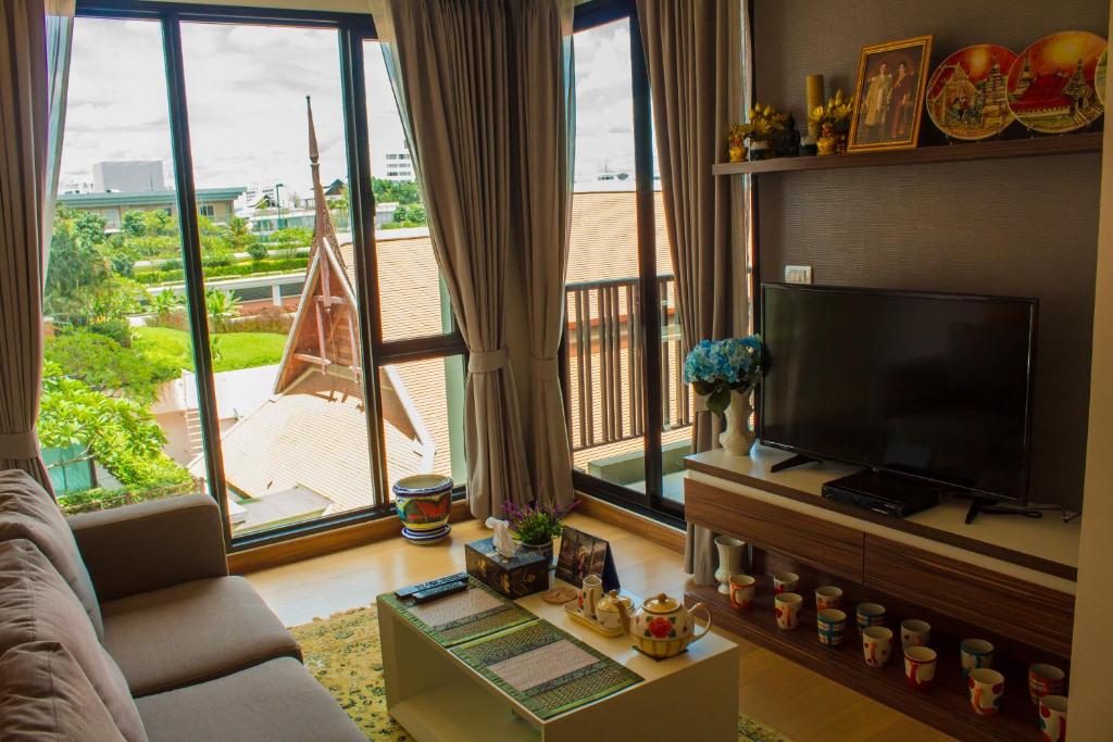een woonkamer met een flatscreen-tv en grote ramen bij 1b-design-50sqm-Astra-ChiangMai in Chiang Mai