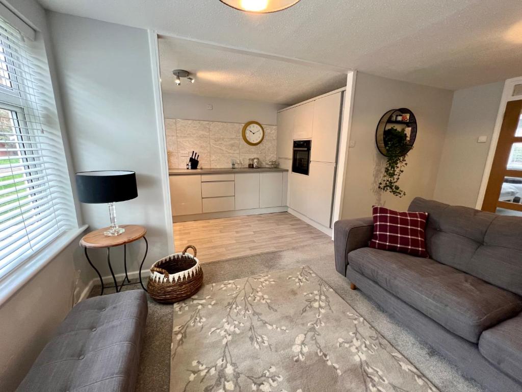 een woonkamer met een bank en een tafel en een keuken bij Chic 2BR Haven - Contemporary Flat in Hoddesdon in Hoddesdon