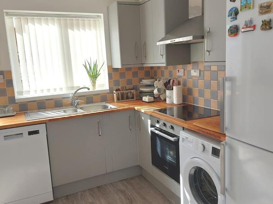 a kitchen with a sink and a washing machine at Comfortable 2 bedroom house in historic Exeter in Exeter