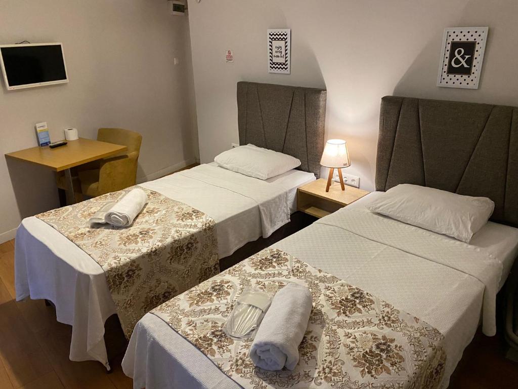 a room with two beds and a table with a lamp at No Problem Pansiyon & Alkaya in Tekirdağ