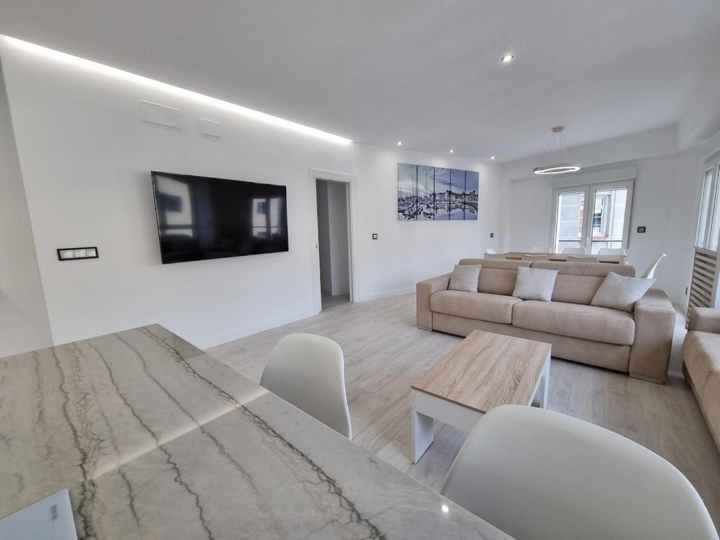 Sala de estar blanca con sofá y mesa en 131A - Espectacular apartamento 8 personas Puerto, en Gijón
