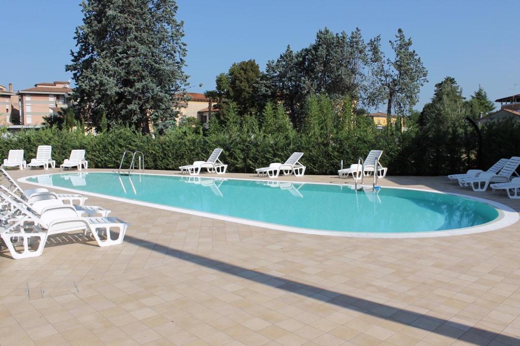 een zwembad met witte ligstoelen en een stapel handdoeken bij Casa di Chiara in Peschiera del Garda