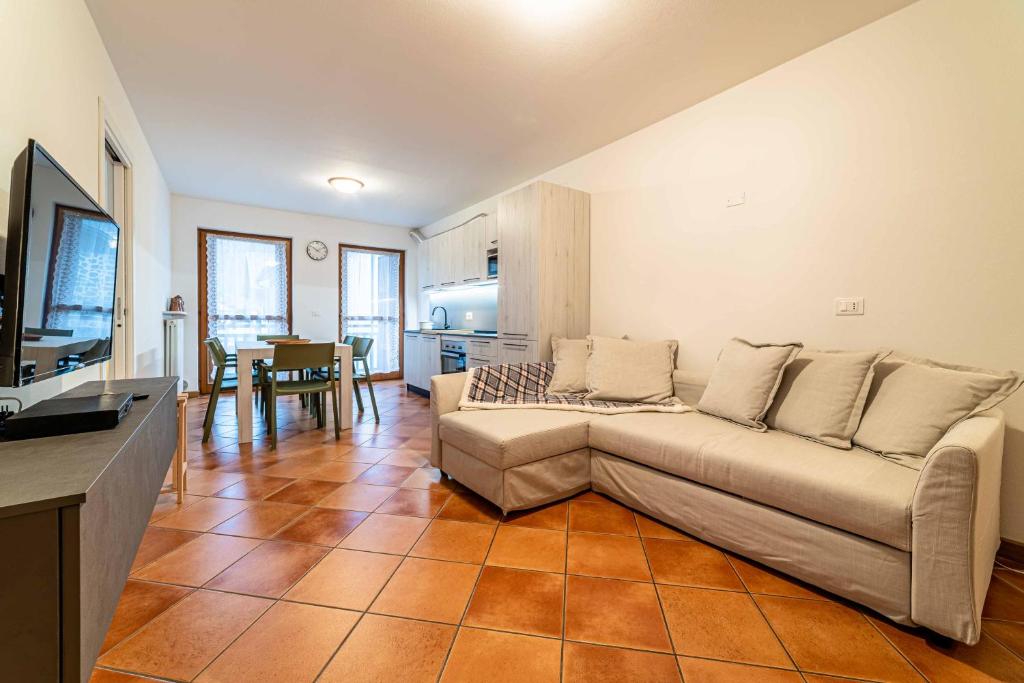 uma sala de estar com um sofá e uma cozinha em Appartamento Dolomia em Caprile
