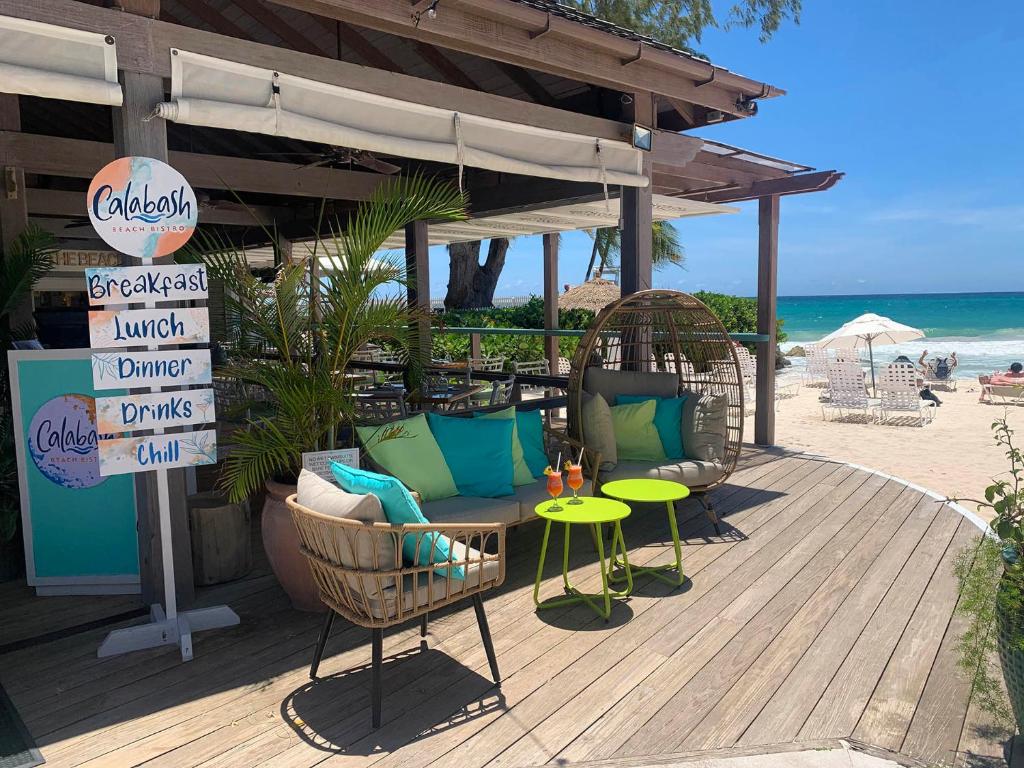 a wooden deck with chairs and a table on the beach at Bougainvillea Barbados in Christ Church