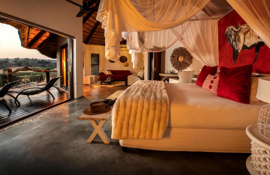 a bedroom with a bed and a living room at Pondoro Game Lodge in Balule Game Reserve