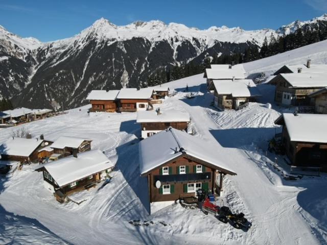 un pueblo cubierto de nieve con montañas en el fondo en Kuschelhüsli Ganahl Wohnung Zamangspitze, en Aussersiggam